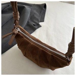 Close-up of brown suede croissant bag showing vertical stitching and metal zipper