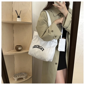 Vue détaillée du grand sac cabas en toile blanche avec texte et petite pochette assortie