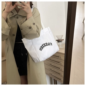 Détail du grand sac cabas en toile blanche avec lettrage noir tendance et style décontracté