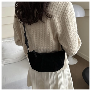 Detail of vintage matte black crescent bag with knotted strap on model in neutral room
