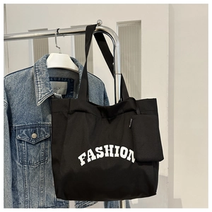 Détail d'un grand sac fourre-tout en toile noire avec imprimé FASHION et porte-monnaie