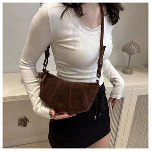Detailed view of the knotted strap and matte texture on this brown crescent shoulder bag