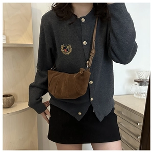 Detail showing the brown suede crossbody crescent bag with natural pleated texture