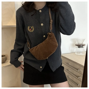 Brown suede crescent bag with knot detail worn crossbody in a cozy lifestyle setting