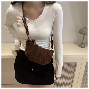 Detail of a dark brown suede crescent bag with pleated design and slim shoulder strap