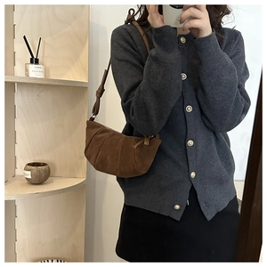 Detail of a brown suede crescent bag with vertical pleated stitching and a slim strap