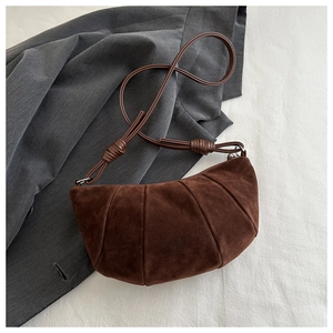 Macro detail of brown suede crescent bag featuring vertical stitching and knotted strap