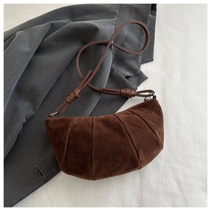 Macro detail of brown suede crescent bag featuring pleated design and knotted strap style