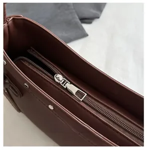Detailed view of the smooth silver zipper and rivets on this vintage brown hobo bag