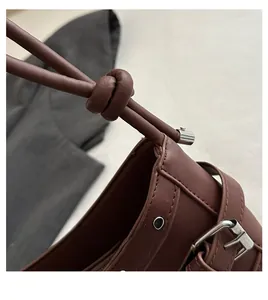Close-up of brown matte leather baguette bag showing stitching and knot handle detail