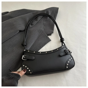 Detail of black faux leather underarm bag with silver studs and belt buckle accents