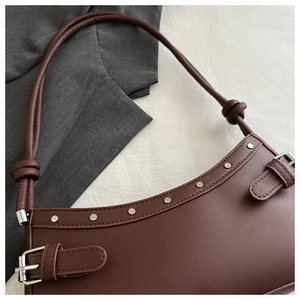 Close-up of deep brown underarm bag with silver studs and knotted shoulder strap detail