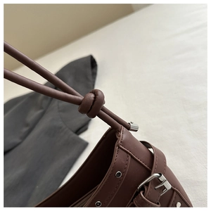 Detail of brown shoulder bag showing knotted strap and silver metallic rivets