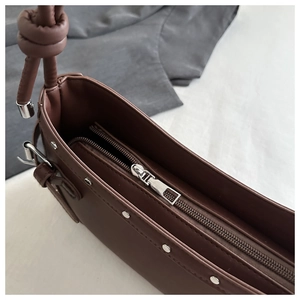 Detail view of brown leather shoulder bag featuring a knotted strap and silver metal hardware