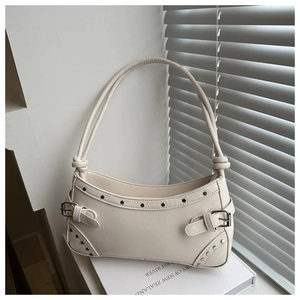 Detail view of cream leather shoulder bag featuring silver rivets and metal buckle hardware