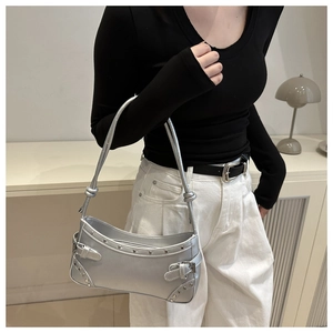 Detail of silver metallic Y2K shoulder bag with rivets and knot strap on a model