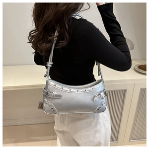 Close-up of metallic silver Y2K shoulder bag featuring punk rivets and buckle details