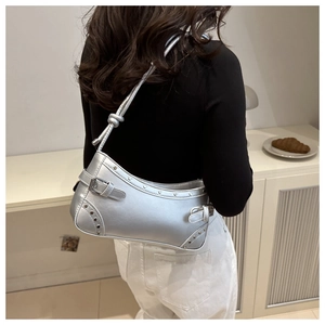 Detailed side view of silver shoulder bag with metallic studs and buckle strap decor