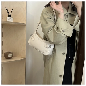 Close-up of white crescent shoulder bag with silver rivets and knotted strap detail