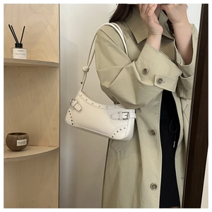 Close-up of white crescent underarm bag with silver studs and adjustable strap detail