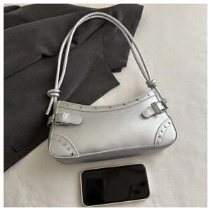 Silver metallic underarm bag with stud detail and belt accents next to a mobile phone