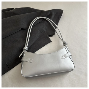 Detail of silver matte underarm bag with double knotted straps on a gray suit jacket