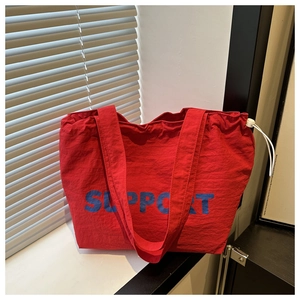 Détail du sac cabas rouge avec inscription SUPPORT bleue et cordon de serrage blanc