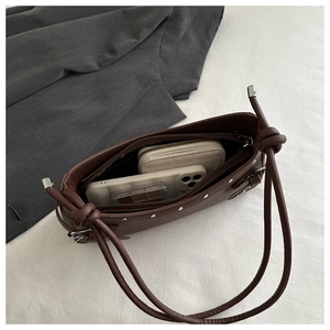 Macro view showing the interior capacity of the dark brown leather shoulder bag with rivets