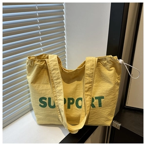 Détail d'un sac cabas en toile jaune avec texte Support vert et cordon de serrage