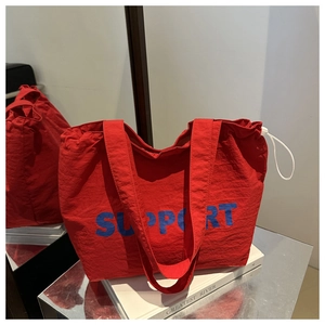 Gros plan du sac cabas en toile rouge avec imprimé SUPPORT et cordon de serrage