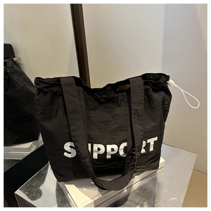 Détail d'un grand sac fourre-tout noir en nylon avec lettrage SUPPORT blanc