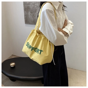 Détail du sac cabas en toile jaune avec texte Support vert et fermeture à cordon pratique
