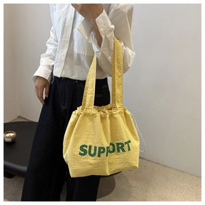 Détail du cabas jaune avec texte Support vert et fermeture à cordon sur l'épaule