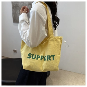 Détail du sac cabas en toile jaune avec lettrage SUPPORT vert et fermeture à cordon