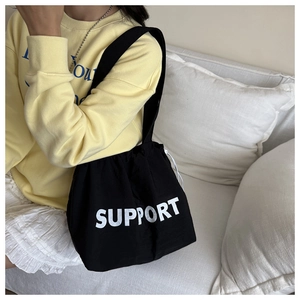Détail d'un sac cabas en toile noire avec logo SUPPORT blanc imprimé sur le côté
