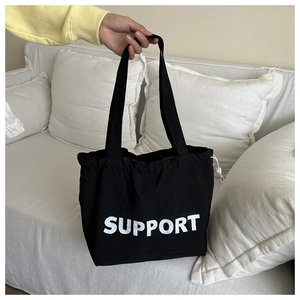 Détail du sac cabas en toile noire avec lettrage SUPPORT et cordon de serrage