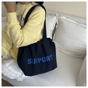 Détail d'un sac cabas en nylon noir avec imprimé bleu SUPPORT et cordon blanc de serrage