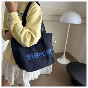 Détail du sac cabas bleu marine avec texte Support et cordon de serrage blanc