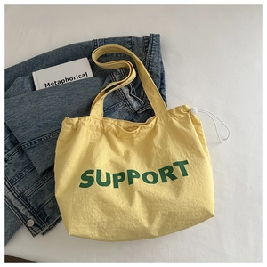 Détail du sac cabas en toile jaune avec texte Support vert et cordon blanc