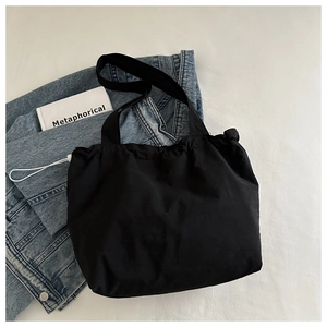 Détail du sac cabas noir à cordon avec cordon réglable sur fond en jean décontracté