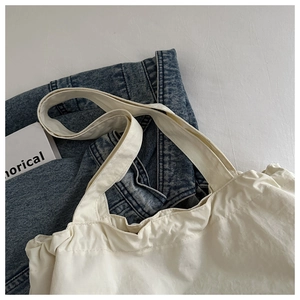 Détails des poignées d'un sac cabas en toile blanche avec texture et décor épuré
