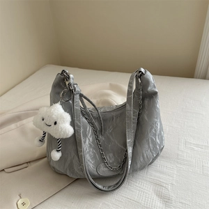 Grey metallic pleated hobo bag with silver chain and white cloud charm on beige bedding