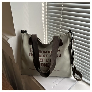 Detail of olive green canvas tote bag showing fashion text print and durable brown straps