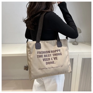 Detailed back view of a large canvas tote bag with artistic lettering on a model
