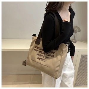 Detail of khaki canvas tote bag with large black fashion typography and brown straps