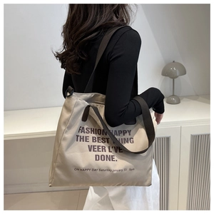 Detailed view of beige canvas tote bag showing large capacity and brown strap detail