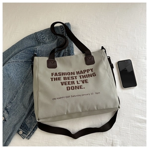 Detail of grey canvas tote bag with brown straps and printed text in a casual setting