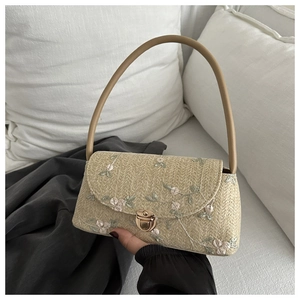 Detail of straw bag with floral embroidery and vintage gold metal clasp closure
