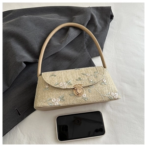 Detail of woven straw bag with floral embroidery and elegant metal clasp closure