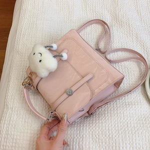 Pink patent leather backpack with cloud charm on white textured background